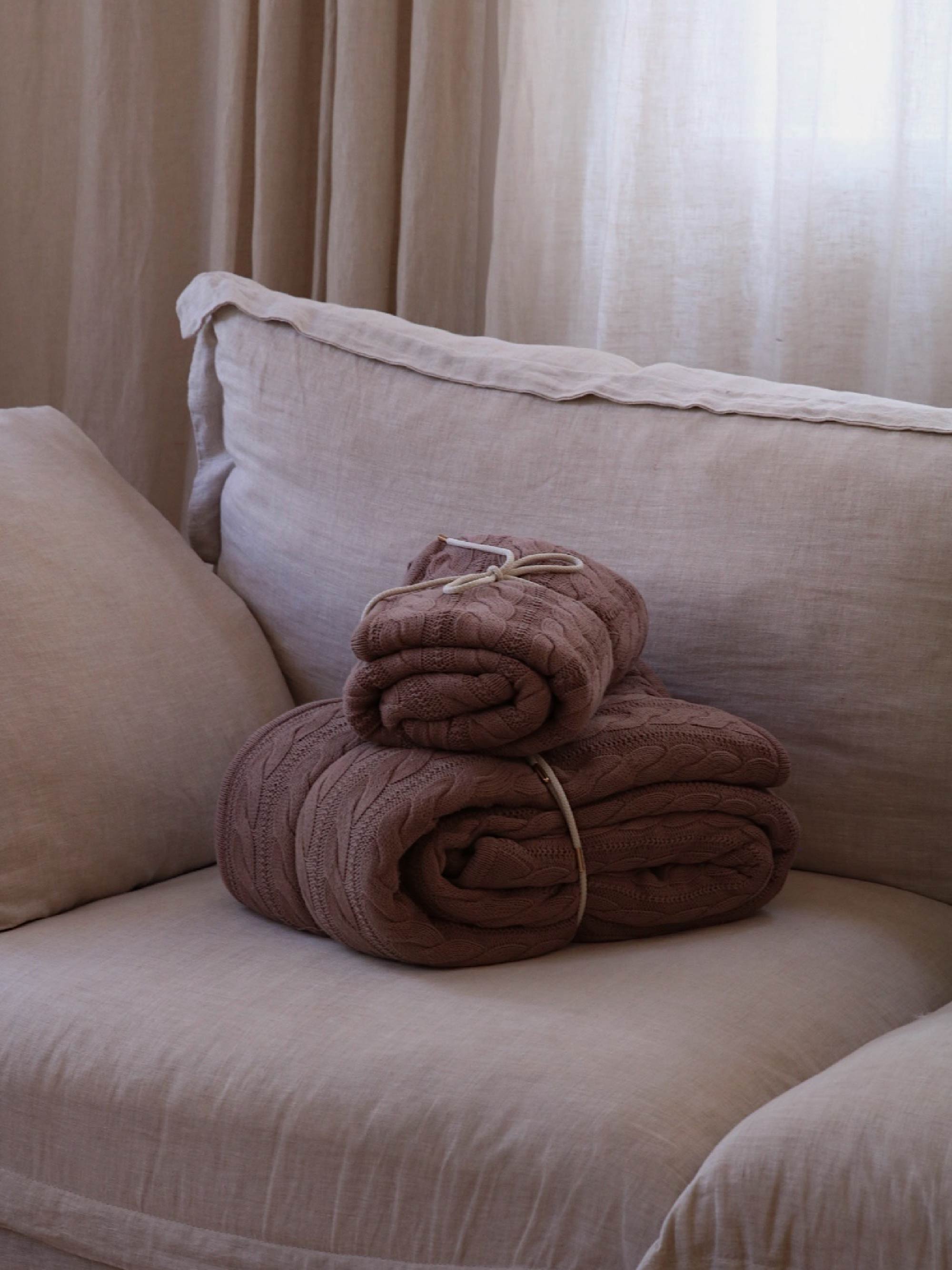TAKEANAP cable knit cotton throw blanket in mocha on a sofa
