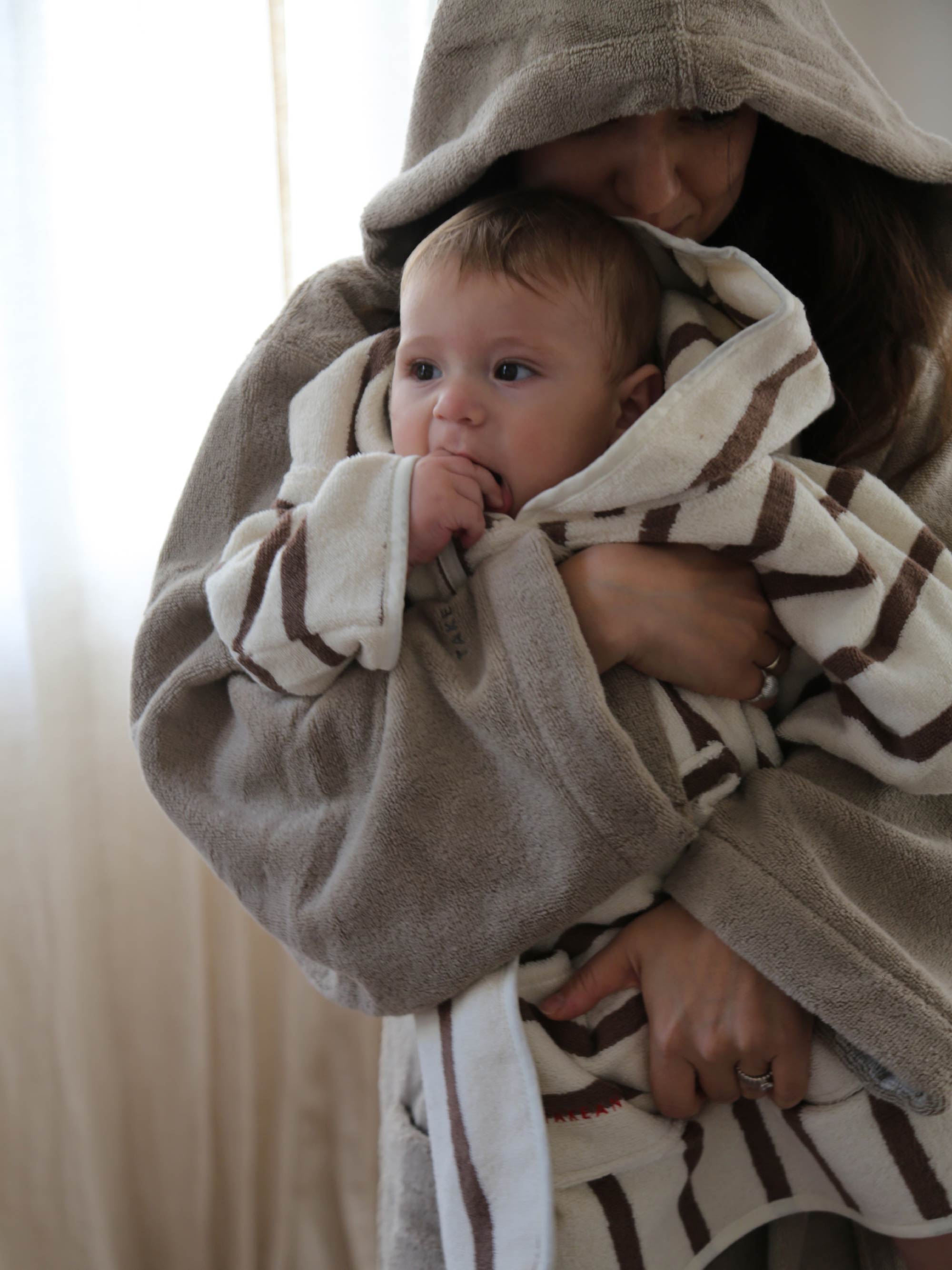 TAKEANAP Stripes hooded baby towel in mocha on a baby