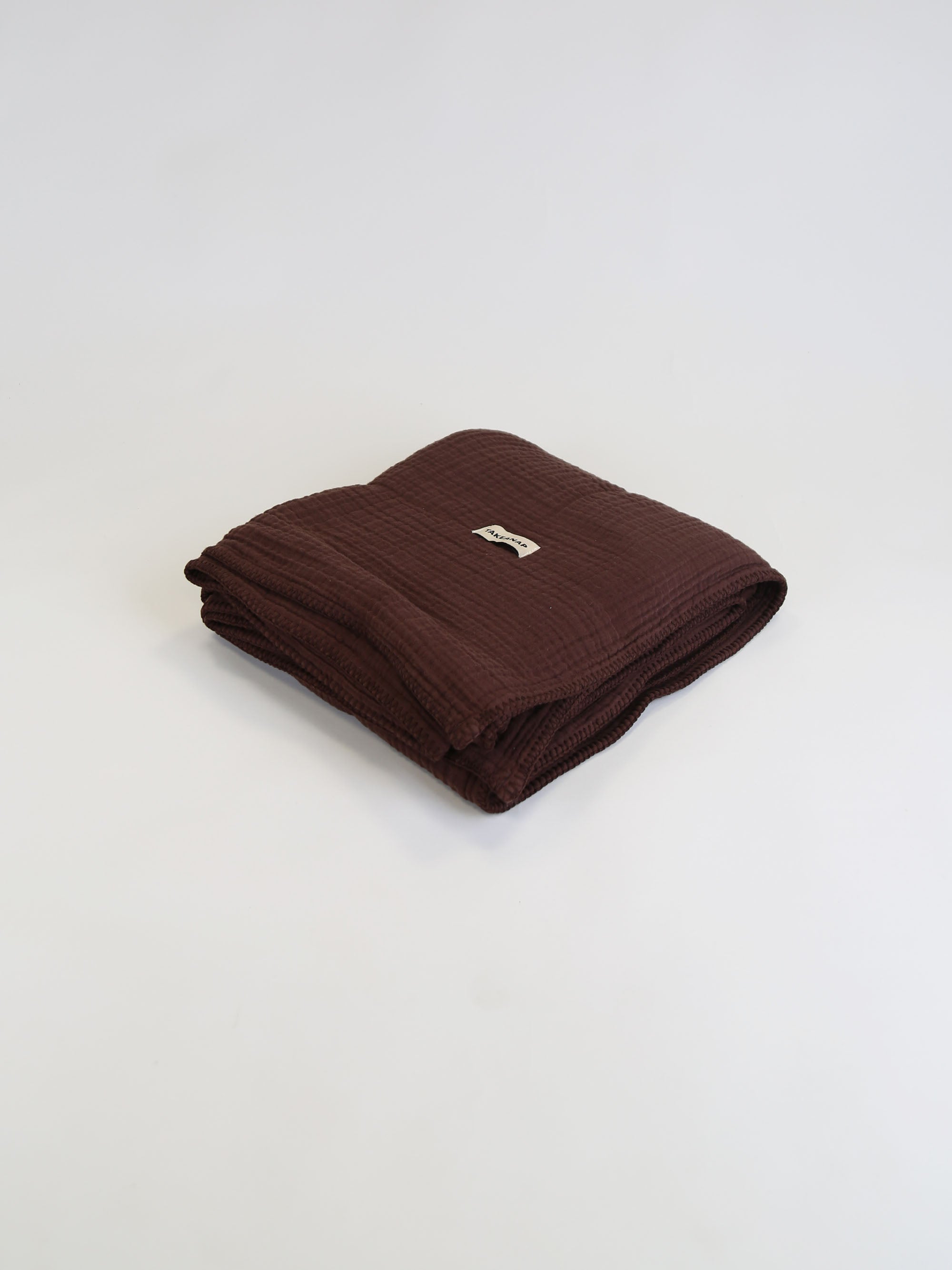 TAKEANAP Dream embroidered muslin coverlet in brownie on a bed