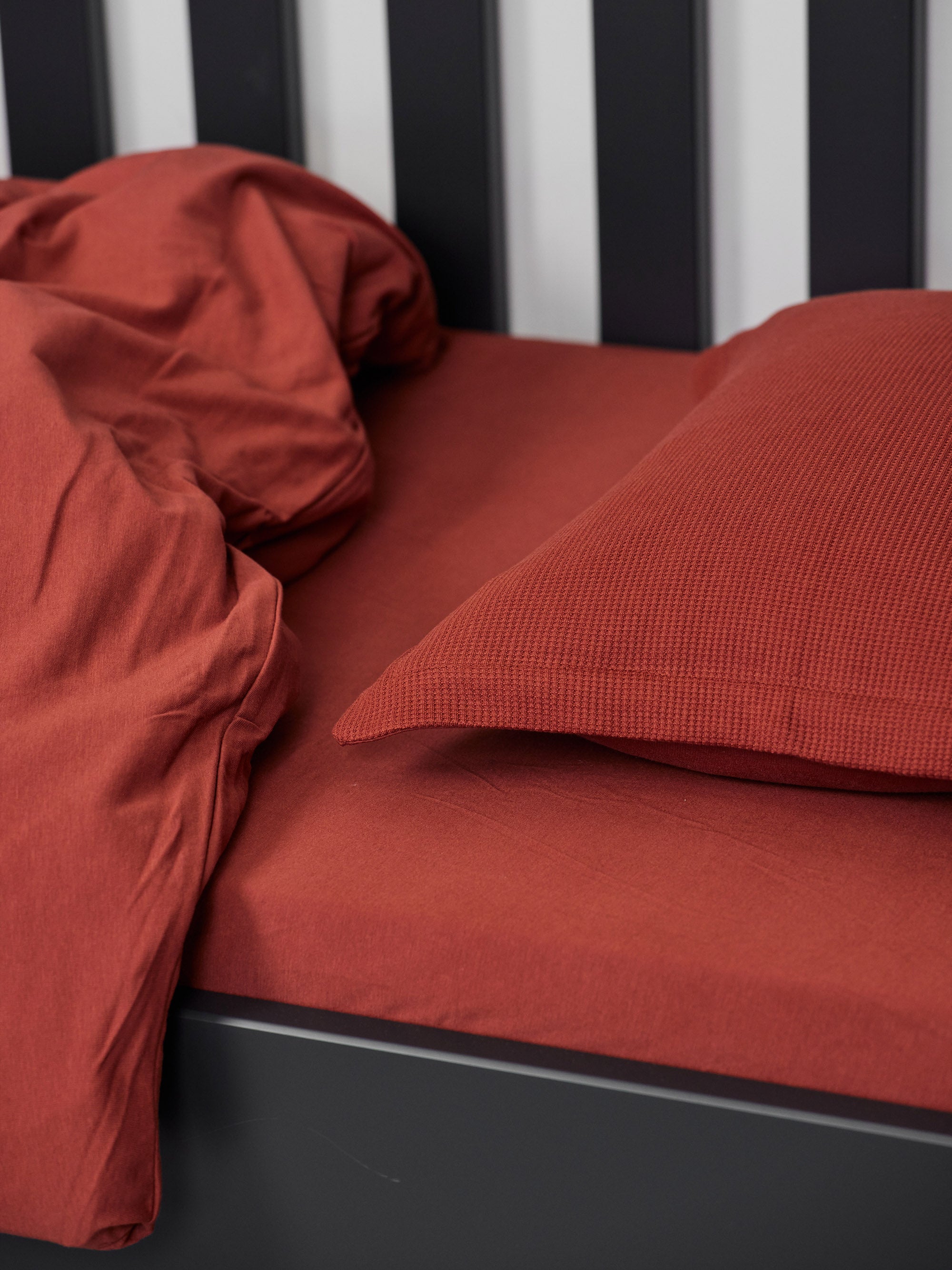Hey welcome 2 JACQUARD | Tabbaco Toddler Pillowcase. Image: Duvet, pillow and pillowcase on a black crib with Tabbaco sheet