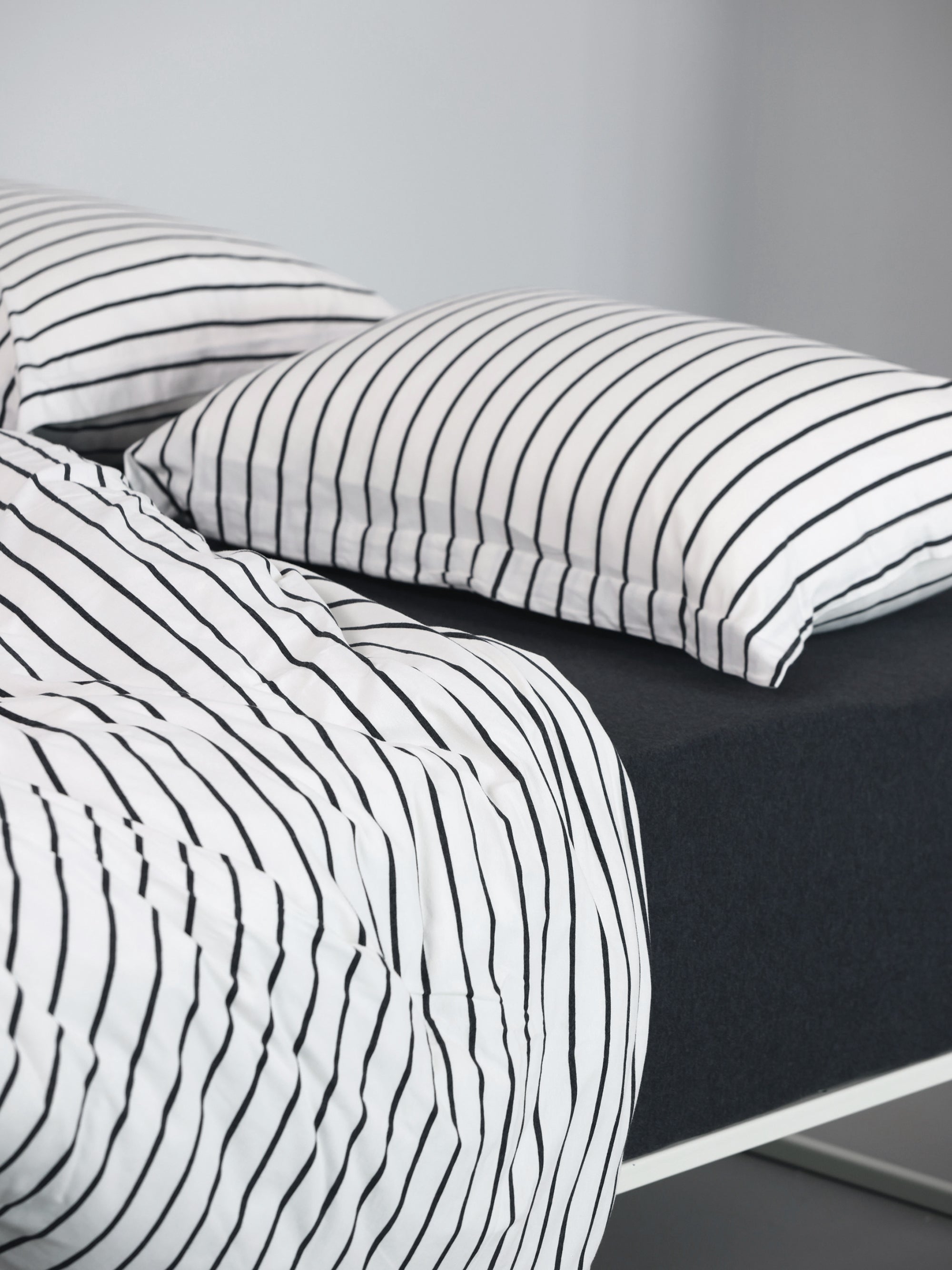 Hey youre on Duvet Set | Stripes product page. Image:  Twin / light gray stripes duvet insert, jersey sheet and 2 pillows with pillowcases on a white frame bed 