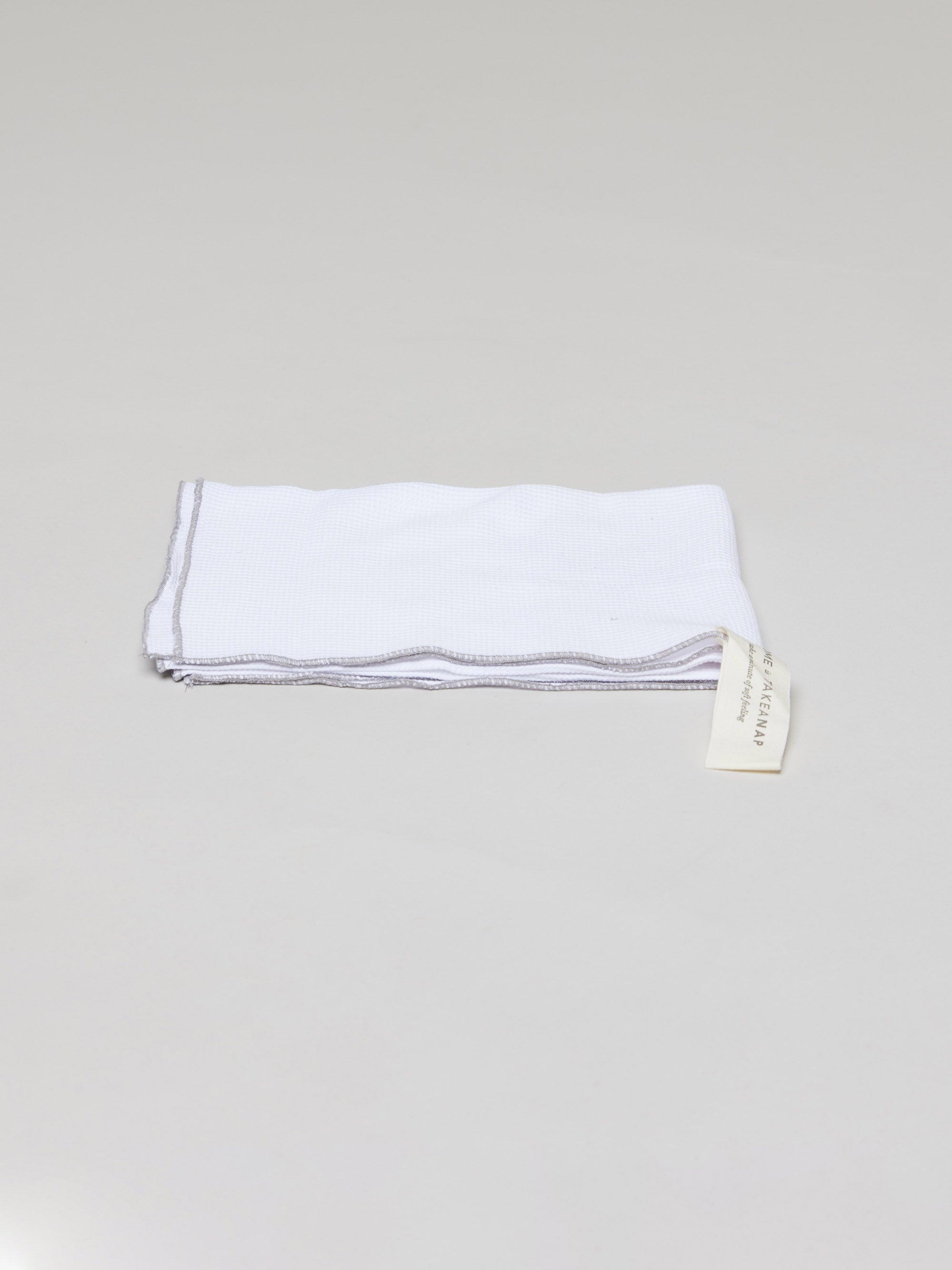 Hey welcome 2 JACQUARD | Kitchen Towel product page. Image: Folded white kitchen towel on a grey light background