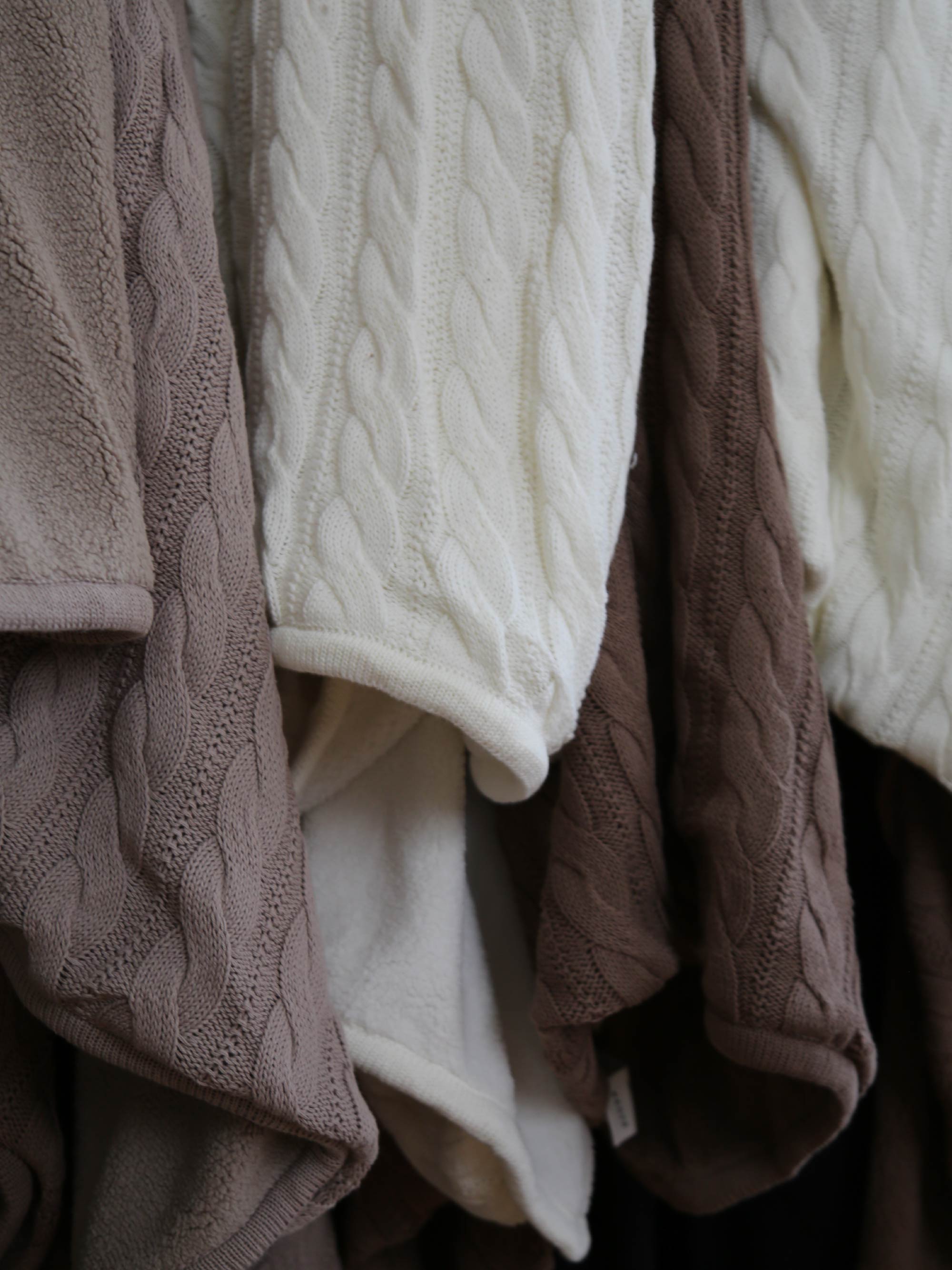 TAKEANAP cable knit cotton throw blanket in ivory on a sofa