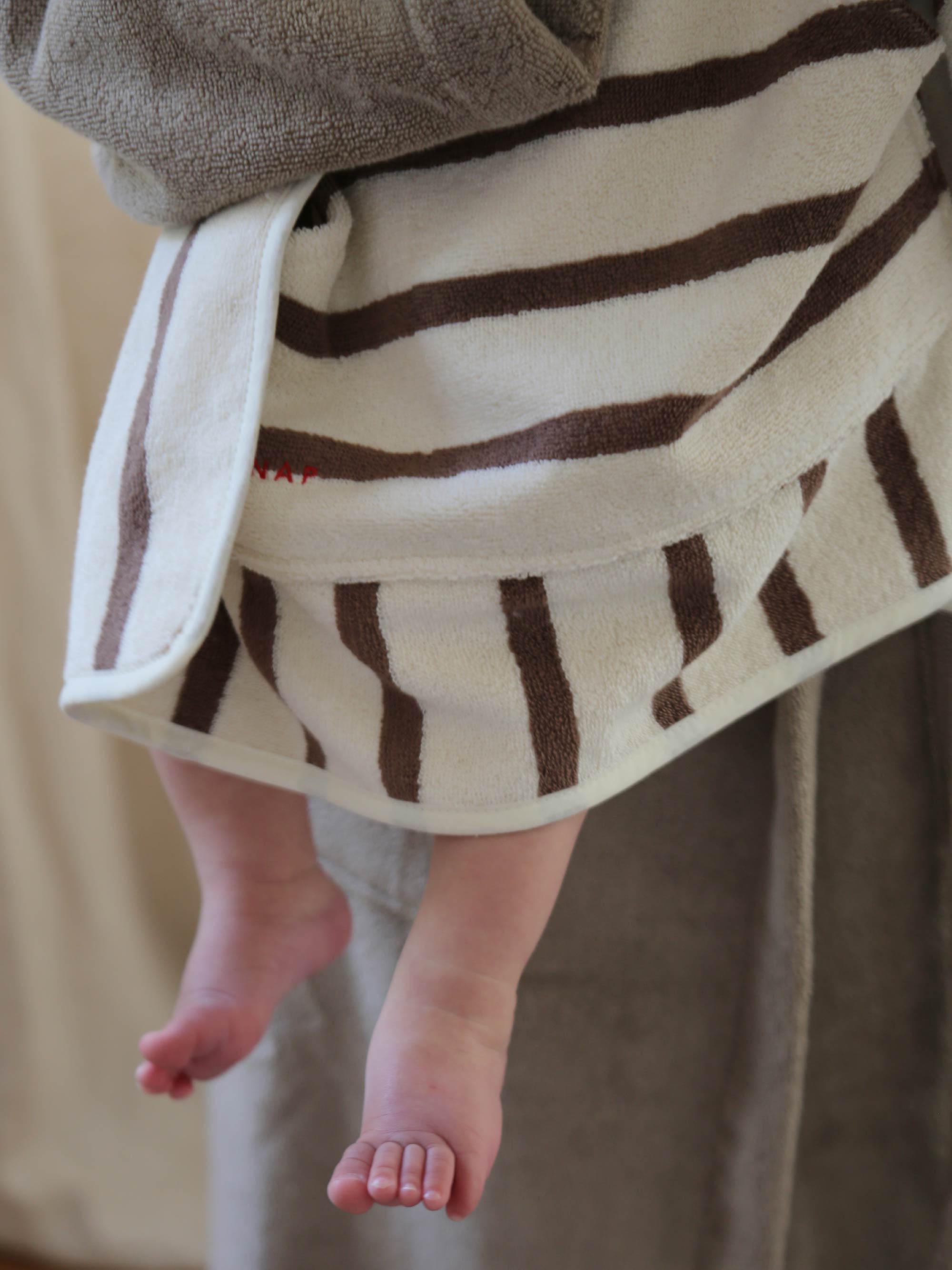 TAKEANAP Stripes hooded baby towel in mocha on a baby