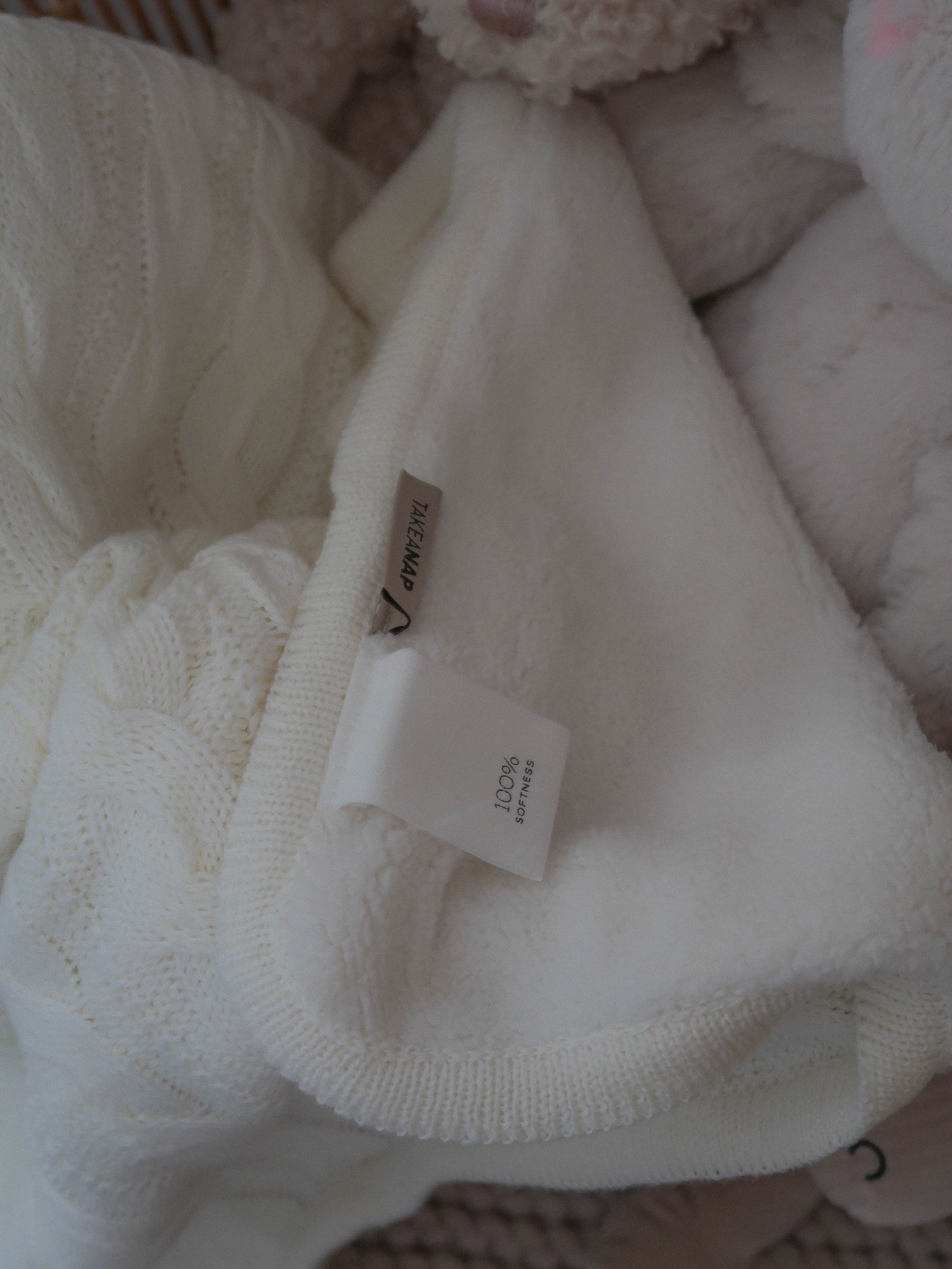 TAKEANAP cable knit cotton throw blanket in ivory on a sofa